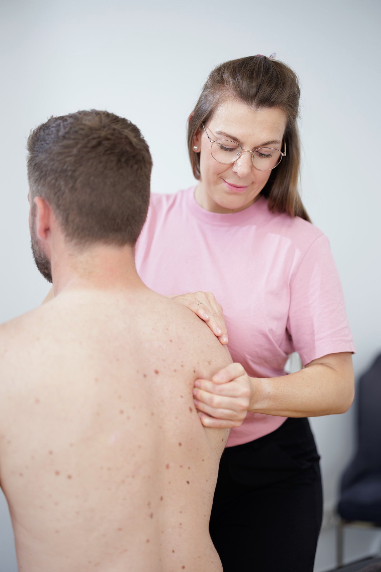 Physiotherapeutin behandelt die Schultermuskulatur eines Patienten